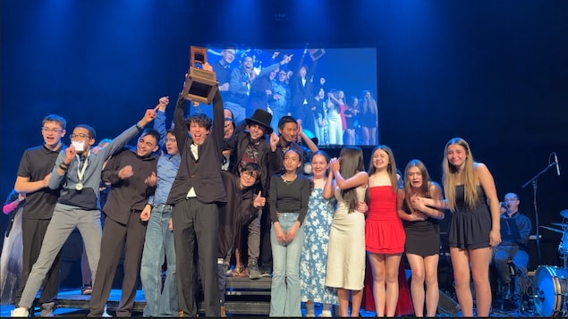 Des lauréats brandissent avec enthousiasme leur trophée lors de la soirée de gala, marquant la clôture du Festival théâtre jeunesse. 