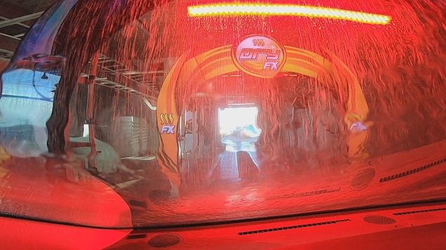 Une vue de l'intérieur de la voiture alors qu'elle traverse le lave-auto illuminé d'une couleur rouge vive.