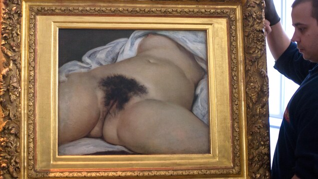 Un employé transporte le tableau représentant le tronc d'une femme nue, couchée sur le dos, les jambes écartées laissant voir son sexe.