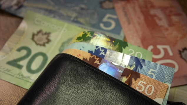 Un porte-feuille et des billets de banque sont déposés sur une table.