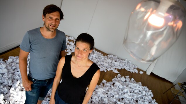 Les artistes dans une pièce avec au sol des centaines de feuilles de papier chiffonnées