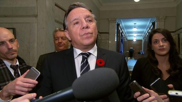 Plan rapproché de François Legault répondant à des questions de journalistes dans les couloirs de l'Assemblée nationale.