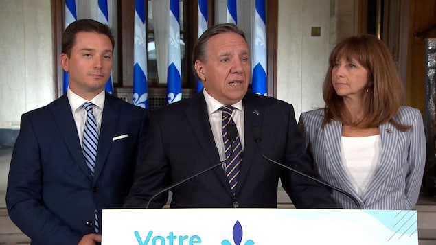 Le premier ministre Legault parle au micro en compagnie de Simon Jolin-Barrette et de Nathalie Roy.