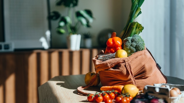 Sac à provisions réutilisable et écologique avec des légumes frais multicolores et des produits d'épicerie sur la table à la maison.