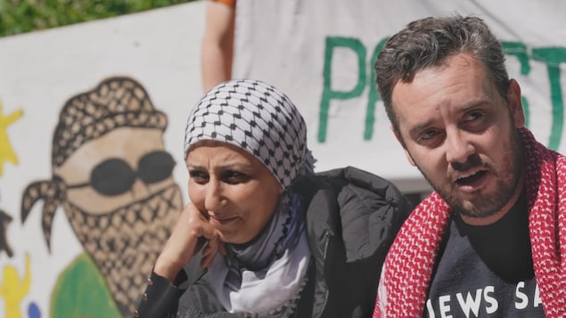 Une femme et un homme devant des banderoles pro-palestiniennes.