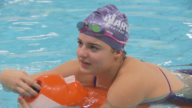 Une jeune femme dans une piscine se laisse flotter sur un mannequin orange. Une jeune femme dans une piscine se laisse flotter sur un mannequin orange.