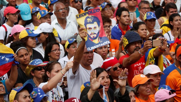Un homme brandit une affiche avec le visage de Leopoldo Lopez, au milieu d'une foule de manifestants