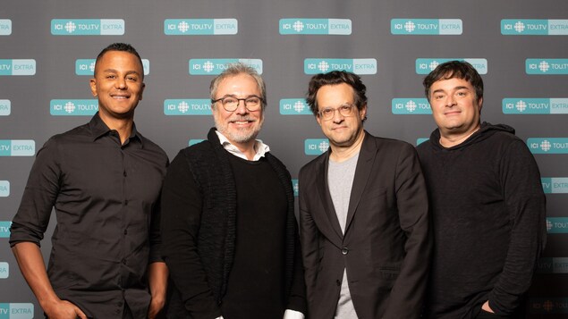 Les quatre hommes sourient à la caméra.