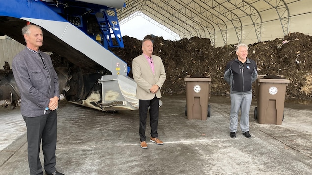 Trois hommes devant le nouveau centre de compostage.