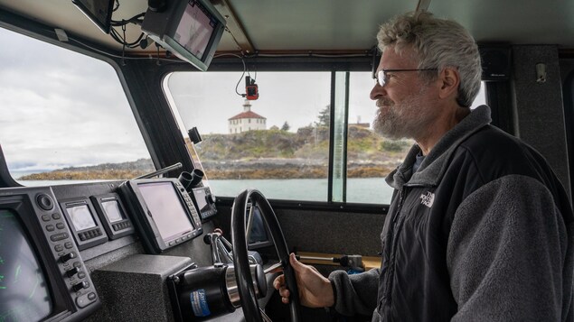 Portrait de Larry Talley en train de conduire, dans le fond, par la fenêtre le phare Eldred Rock en Alaska, juillet 2022.