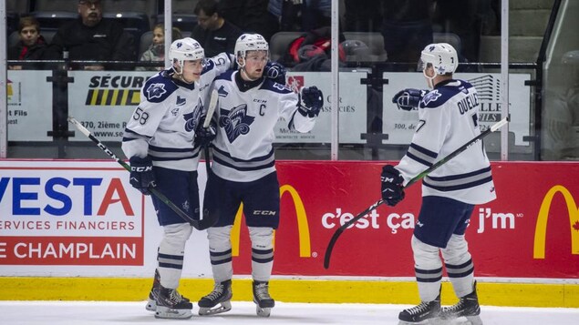 Trois joueurs de l'Océanic se félicitent sur la glace.