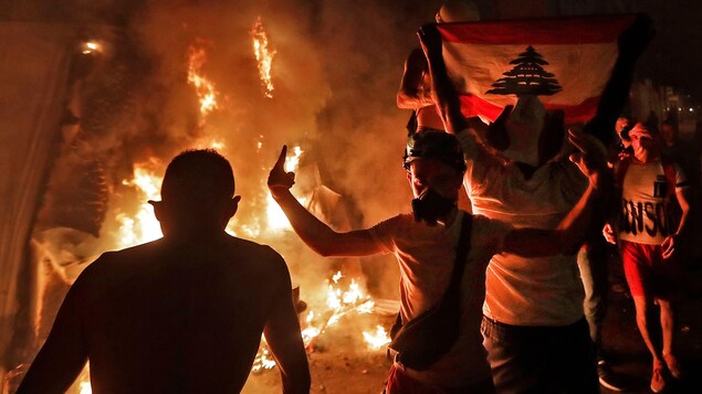 Plusieurs personnes gesticulent autour d'un feu.