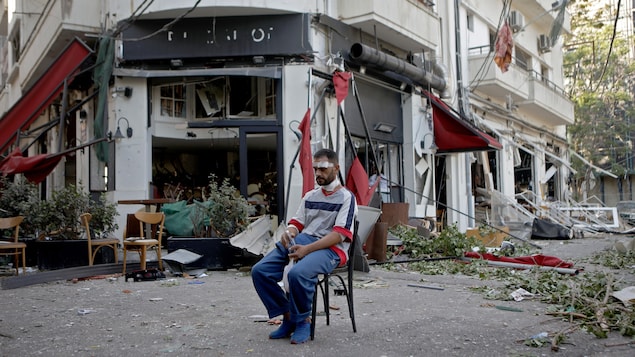 Un homme blessé est assis à côté d'un restaurant dans le quartier de Mar Mikhael à Beyrouth au lendemain de l’explosion.