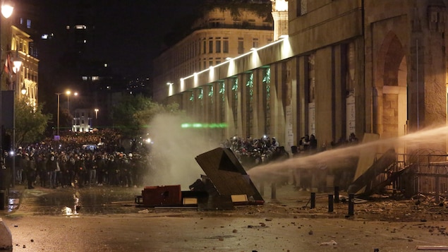 Des manifestants retenus par le jet d'un canon à eau.