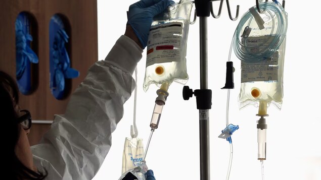 Isang babae na health-care worker inaayos ang IV fluid.