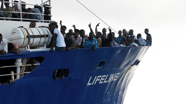 Des migrants se tiennent debout sur le pont du bateau. Des migrants se tiennent debout sur le pont du bateau.