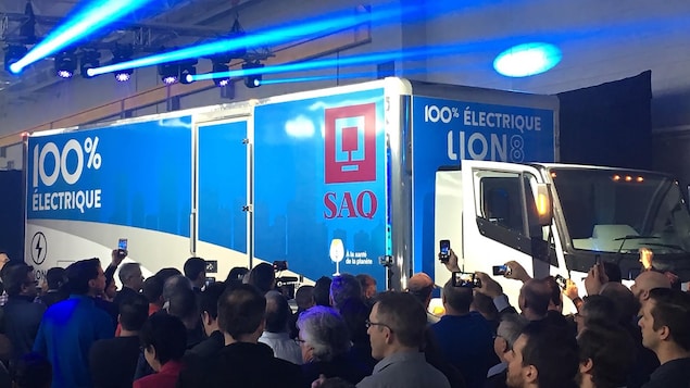 Les travailleurs de l'usine filment le dévoilement du camion avec leur téléphone.
