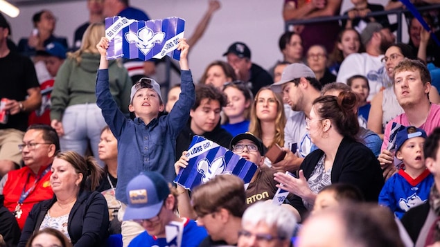 Des partisans brandissent des affiches sur lesquelles on peut lire « Go Lions Go! »