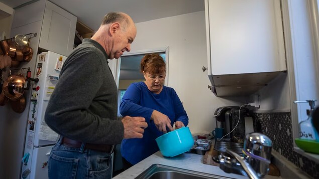 Debout dans la cuisine, Lisa Garner aide son client Paul à préparer son repas.
