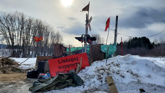 Un campement sommaire, formé de planches de bois et de toiles de plastique, a été érigé sur la voie ferrée.