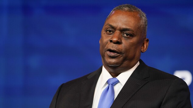 Le général à la retraite Lloyd Austin, s'adressant aux reporters devant un écran bleu.