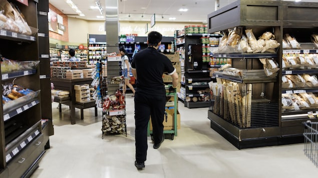 Un employé pousse un panier à l'intérieur d'une épicerie à Toronto.