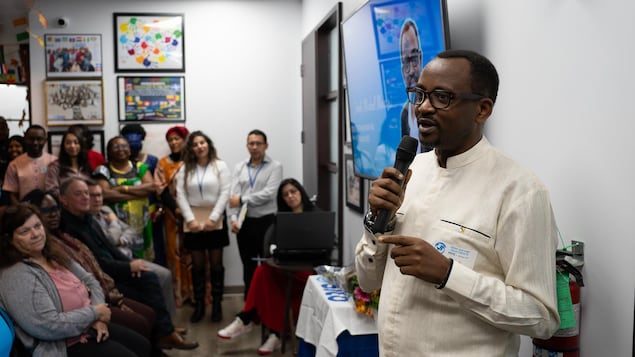 Jordi Musoni s’adresse à une vingtaine de personnes avec un micro. Derrière lui se trouve un écran qui affiche son visage et l’attestation selon laquelle il a complété avec succès la formation préparatoire à l'emploi au Service intégration travail Outaouais.