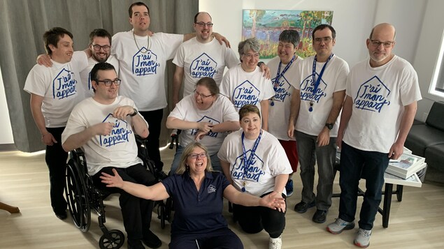 Les onze adultes résidents souriants, en compagnie de la présidente du conseil d'administration de J'ai mon appart', Michèle Lafontaine.