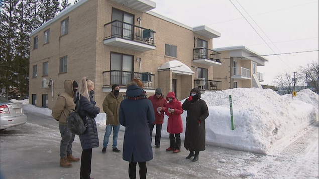 Un groupe de personne discute devant un immeuble à logements