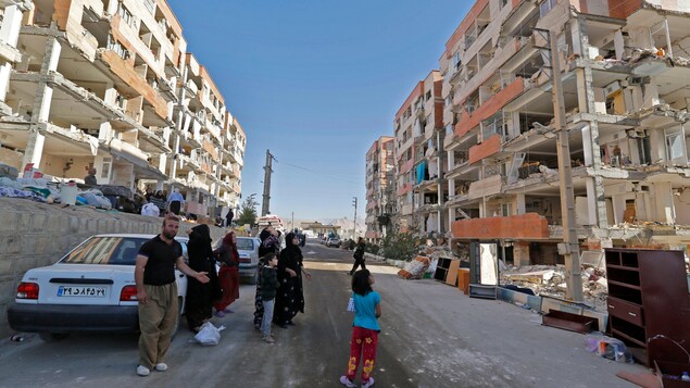 Debout au milieu d'une rue, des résidents de Sar-e Pol-e Zahab constatent que les façades de nombreux immeubles se sont effondrées. Debout au milieu d'une rue, des résidents de Sar-e Pol-e Zahab constatent que les façades de nombreux immeubles se sont effondrées.
