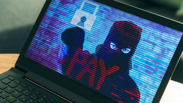 Un écran d'ordinateur montre un pirate informatique qui exige un paiement.