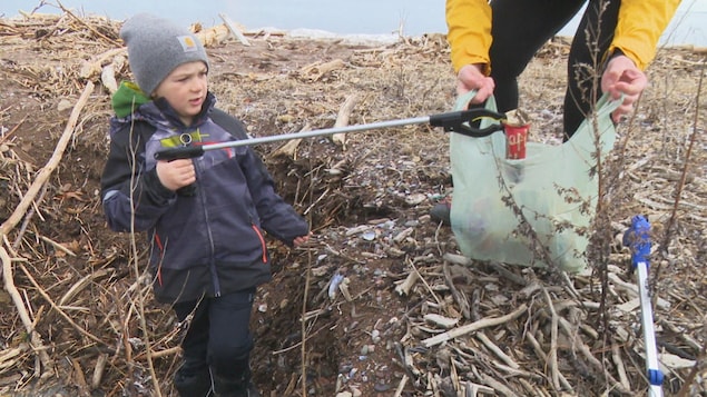 Un bambin ramasse des déchets sur une plage.