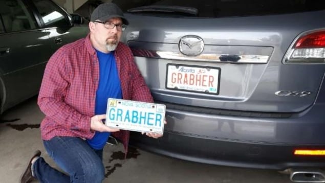 Le fils de Lorne Grabher, Troy, montre la plaque annulée de son père à côté de sa propre plaque, validée en Alberta. Le fils de Lorne Grabher, Troy, montre la plaque annulée de son père à côté de sa propre plaque, validée en Alberta.