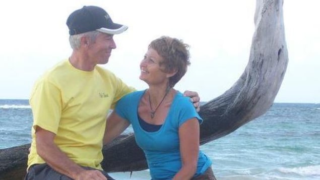 Lorretta Hughes (à droite) et son mari se regardent assis sur un arbre sur une plage avec la mer derrière eux. Lorretta Hughes (à droite) et son mari se regardent assis sur un arbre sur une plage avec la mer derrière eux.