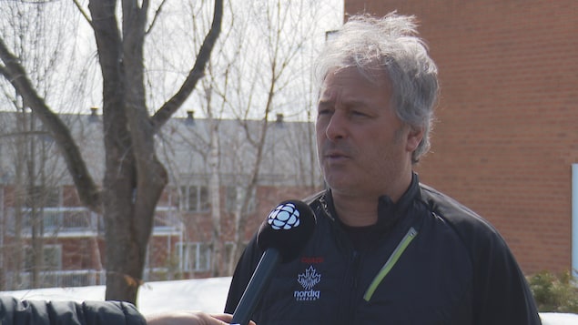 Un homme accorde une entrevue à l'extérieur, au printemps. 