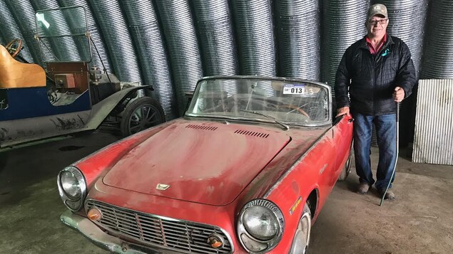 Un homme souriant est debout à côté d'une voiture rouge décapotable Un homme souriant est debout à côté d'une voiture rouge décapotable