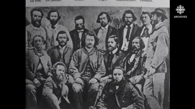 Louis Riel est assis au centre d'un groupe de Métis.