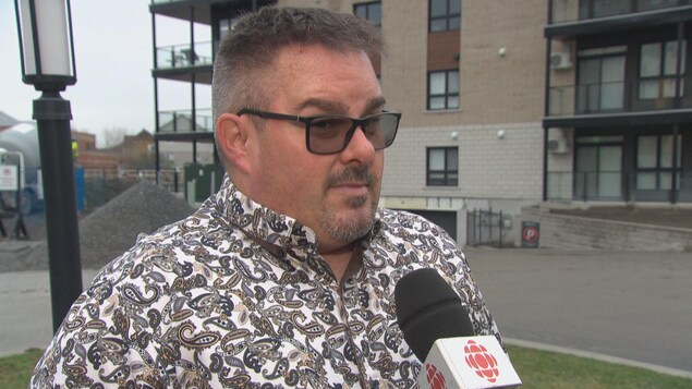 Louis Sauvé en entrevue à Radio-Canada devant un immeuble à logements.