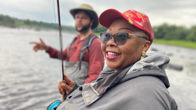 Une dame souriante avec une canne à pêche.