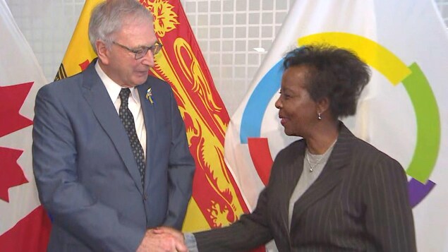 Blaine Higgs et Louise Mushikiwabo se serrent la main devant les caméras.