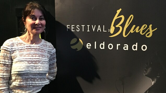 Une femme pose devant une affiche du Festival Blues Eldorado.