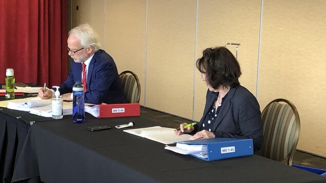 Louisette Langlois consulte des dossiers, assise dans une salle de conférence.