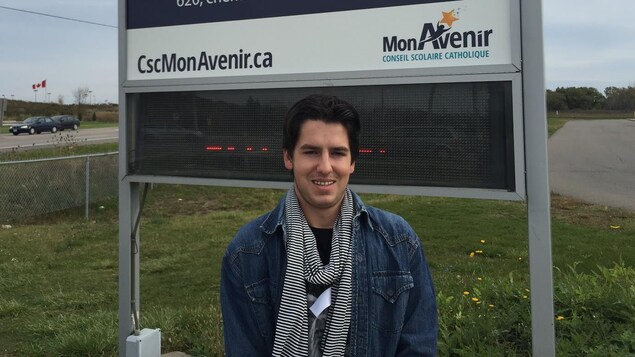 Photo de Luc-Alexandre Grenier devant le panneau de l'école Photo de Luc-Alexandre Grenier devant le panneau de l'école