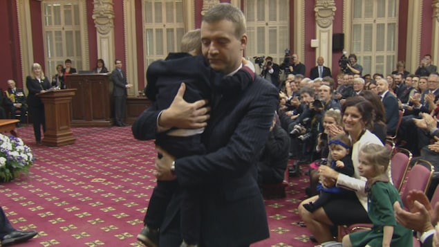 Le député de Sherbrooke et ministre de la Famille, Luc Fortin, avec l'un de ses enfants dans ses bras.