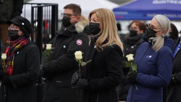 Lucie Garneau se recueillie une fleur à la main avec d'autres proches de victimes endeuillés.