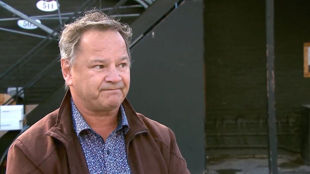 Le propriétaire du bar Kirouac, Lucien Simard, à l'extérieur en entrevue. Il porte un manteau brun