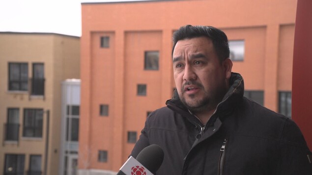 Luis-Carlos Cuasquer parle dans un micro devant un immeuble.