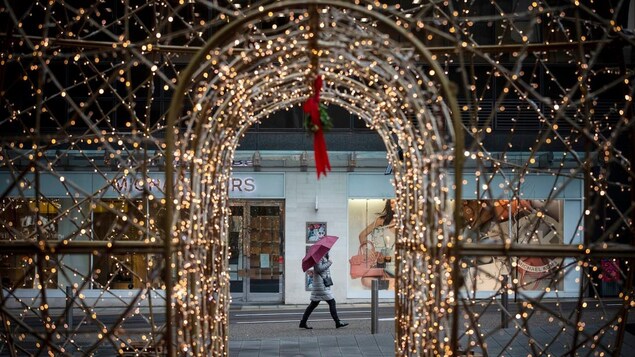 Une femme marche devant des décorations de Noël lumineuses.