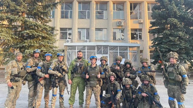Des soldats ukrainiens qui immortalisent devant un bâtiment la reprise de la ville de Lyman qui était tombée aux mains des troupes russes en mai 2022. 