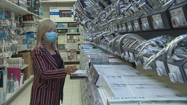 Une femme place des produits dans une allée de magasin.